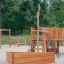 Holz-Spielplatz Schiff Sandkasten mit Rutsche und Klettergerüst in einem Park.